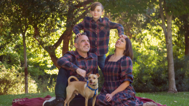 A family in matching plaid garments. The woman in the photo is making a disgruntled face.