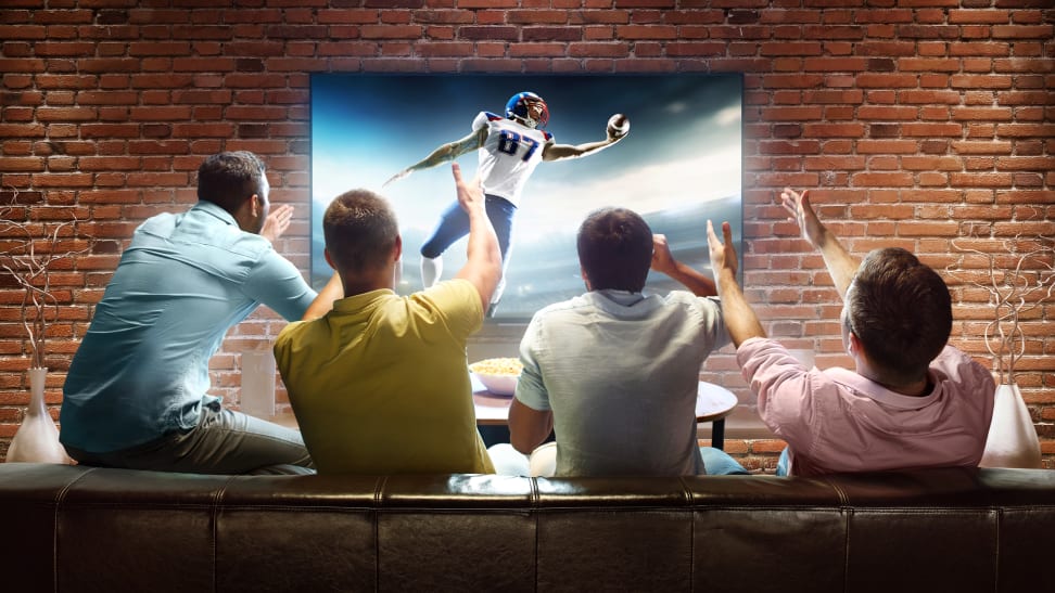 A group of friends celebrating the home team scoring a touchdown in a televised football match