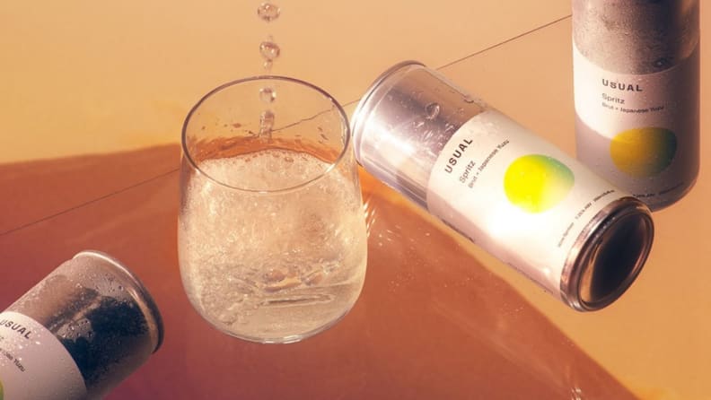Cans of wine spritzers scattered across a warm brown surface.