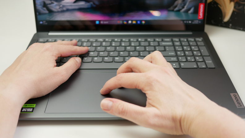 A pair of hands dabbling in the laptop's keyboard and mouse.