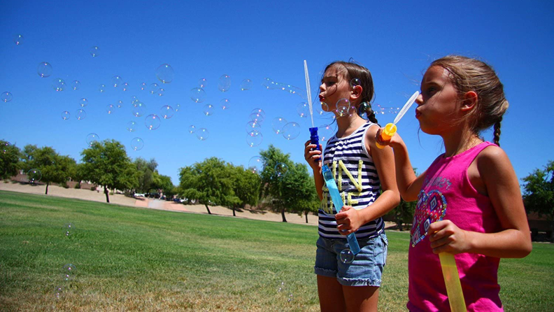 Two girls blowing bubbles with bubble wands