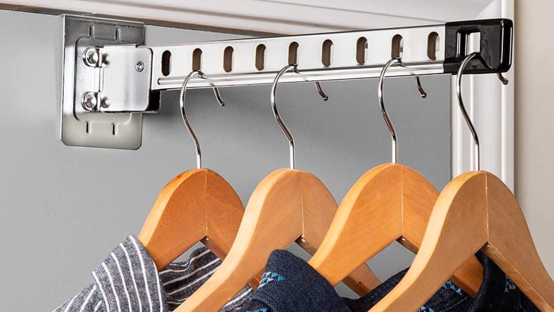 Four shirts hang on hangers in a closet.