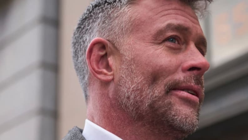 Older man with salt and pepper hair with thin, transparent cable going behind the ear to the Jabra Enhance 700