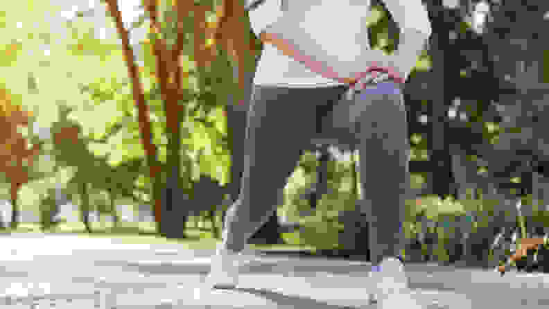 A person is shown (from the abdomen down) performing lunges outdoors.