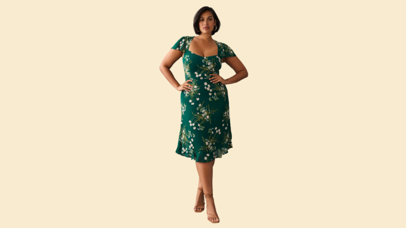 A woman wears a floral green midi dress.