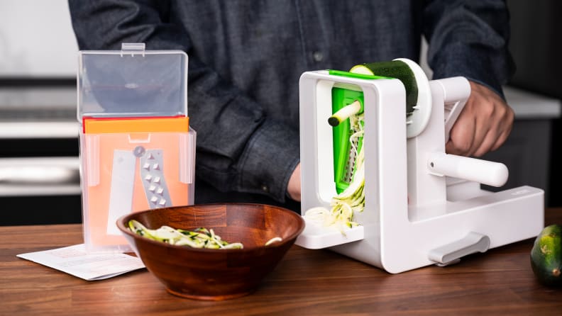 Zoodles fall into a bowl created by the OXO Good Grips Tabletop Spiralizer