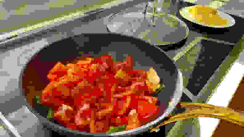 The Frök, filled to the top with diced tomatoes, is sitting on an induction cooktop.