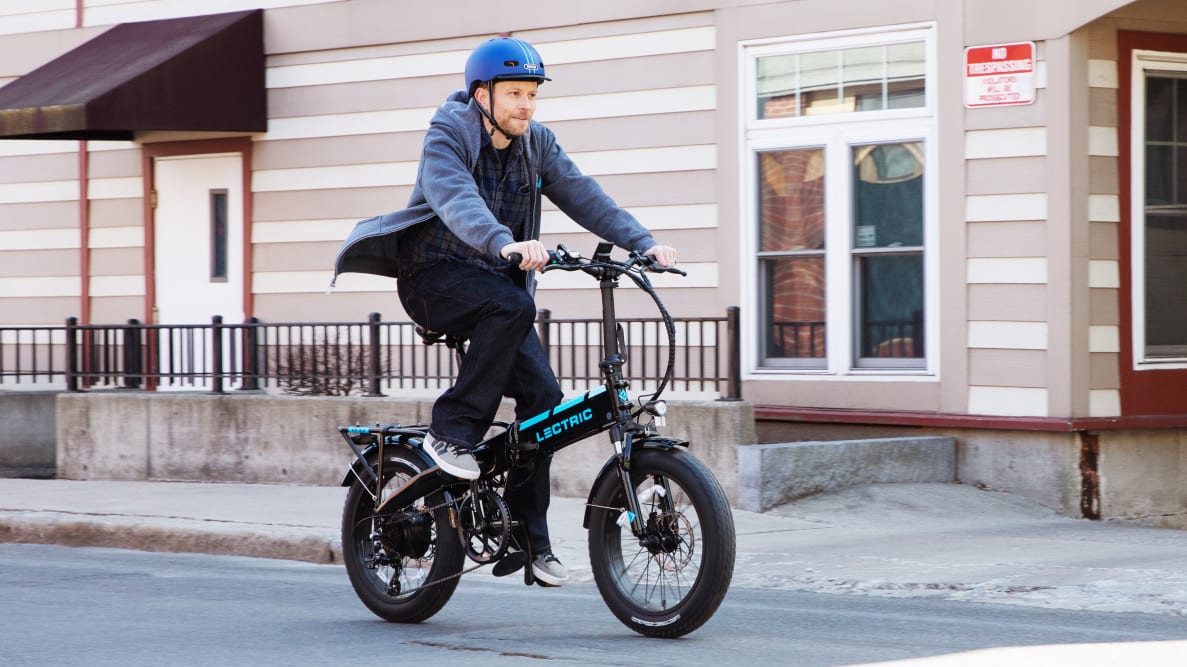 Reviewed chief scientist Dave Ellerby, in a blue helmet, tests out the Lectric XP 3.0 e-bike on the road.