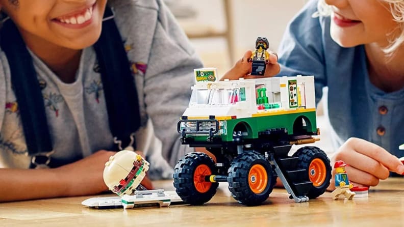 Two children play with a LEGO set on the floor.