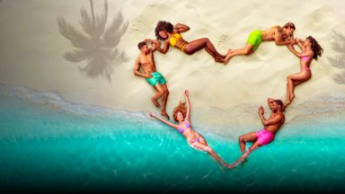 An image of 'Love Island USA' cast members arranged in a heart on a sandy beach.