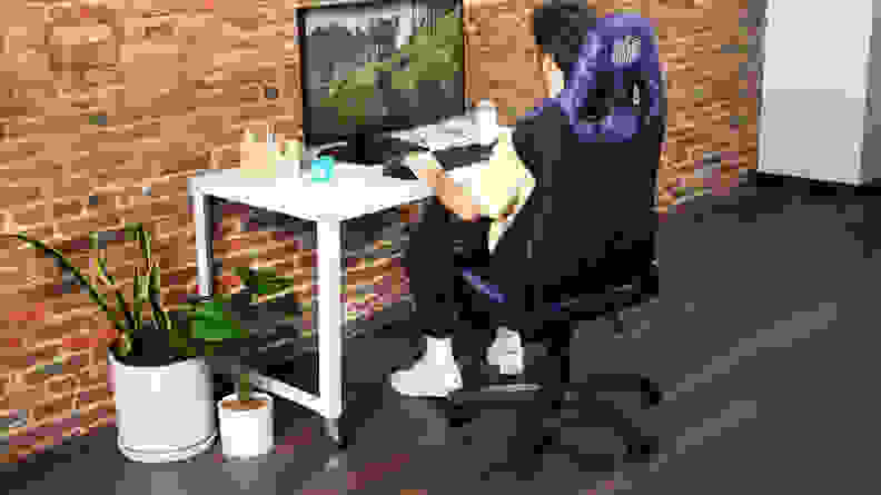 A person sitting in the gaming chair playing a video game in a PC setup.