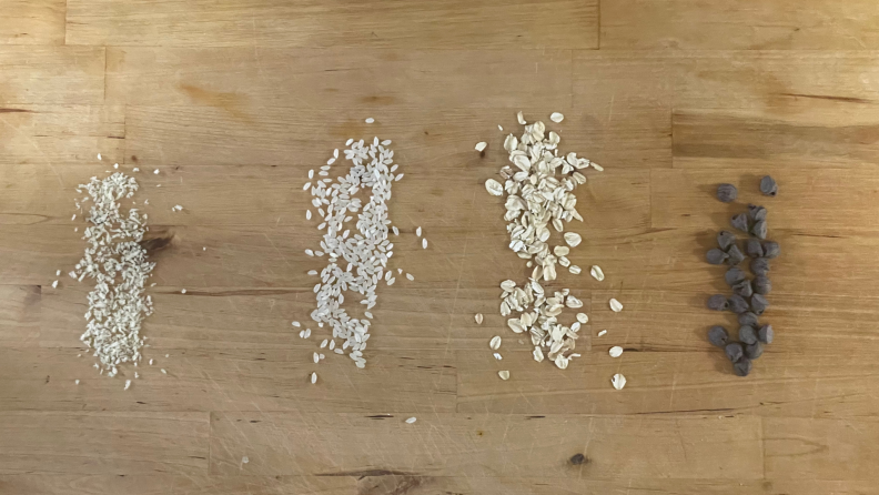 Piles of grits, rice, oats and chocolate chips on countertop.