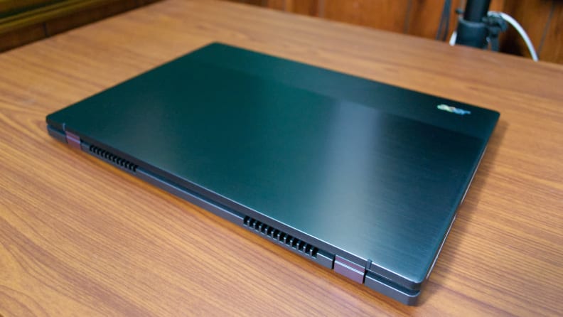 A closed, black laptop on top of a light-brown desk