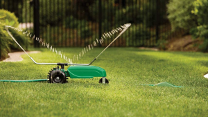 An Orbit traveling sprinkler sprays water on a green grass lawn.