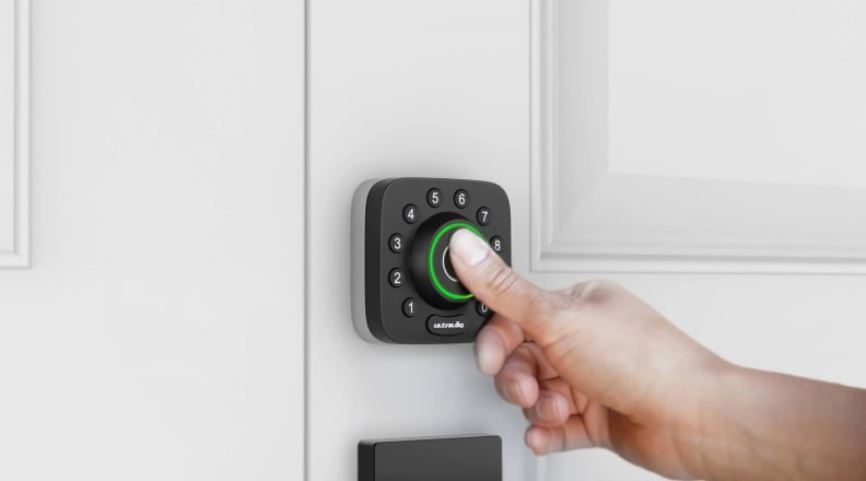 A person's hand pressing a button on a smart door lock
