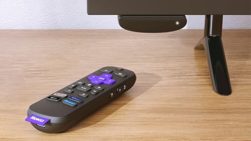 The remote for a Roku Express 4K next to a television with the Express 4K streaming device plugged into said TV.