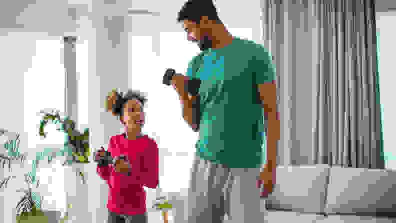 Closeup front view of a young african american man exercising at home. They are lifting some lightweight dumbbells.