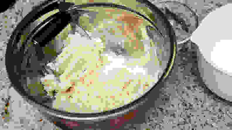 A pastry blender in a pot full of pie dough.