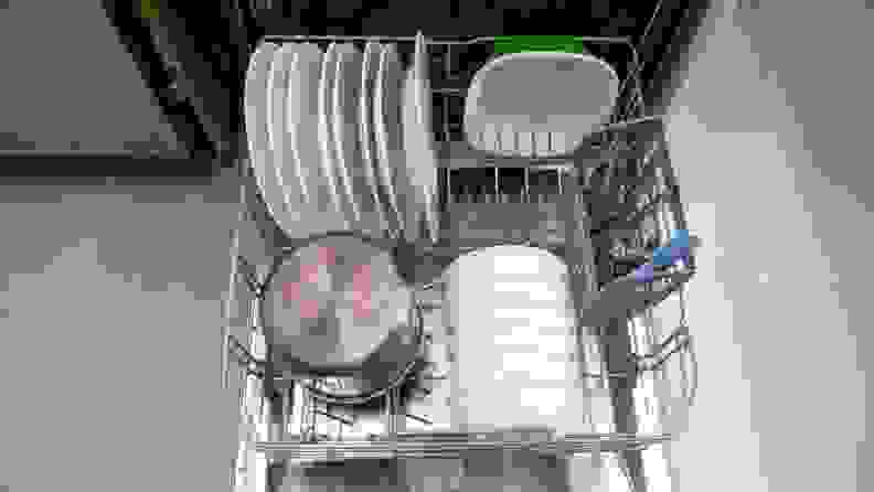 A close-up of the dishwasher's bottom rack, stocked with dishes. You can see a column of foldable tines folded down to make room for a large pot.
