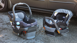 Two car seats sitting on the ground next to a car.