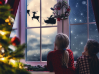 Two children staring out the window looking at Santa fly by the moon.