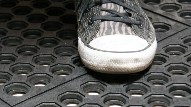 A person steps on a rubber mat.