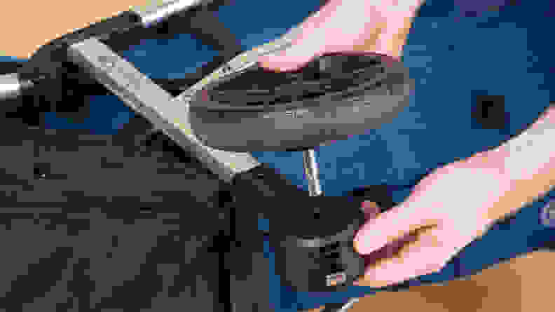 A pair of hands inserting a wheel into the leg of the stroller.