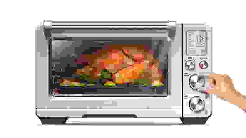Person adjusting the temperature on the Breville Smart Oven as it's roasting a whole chicken