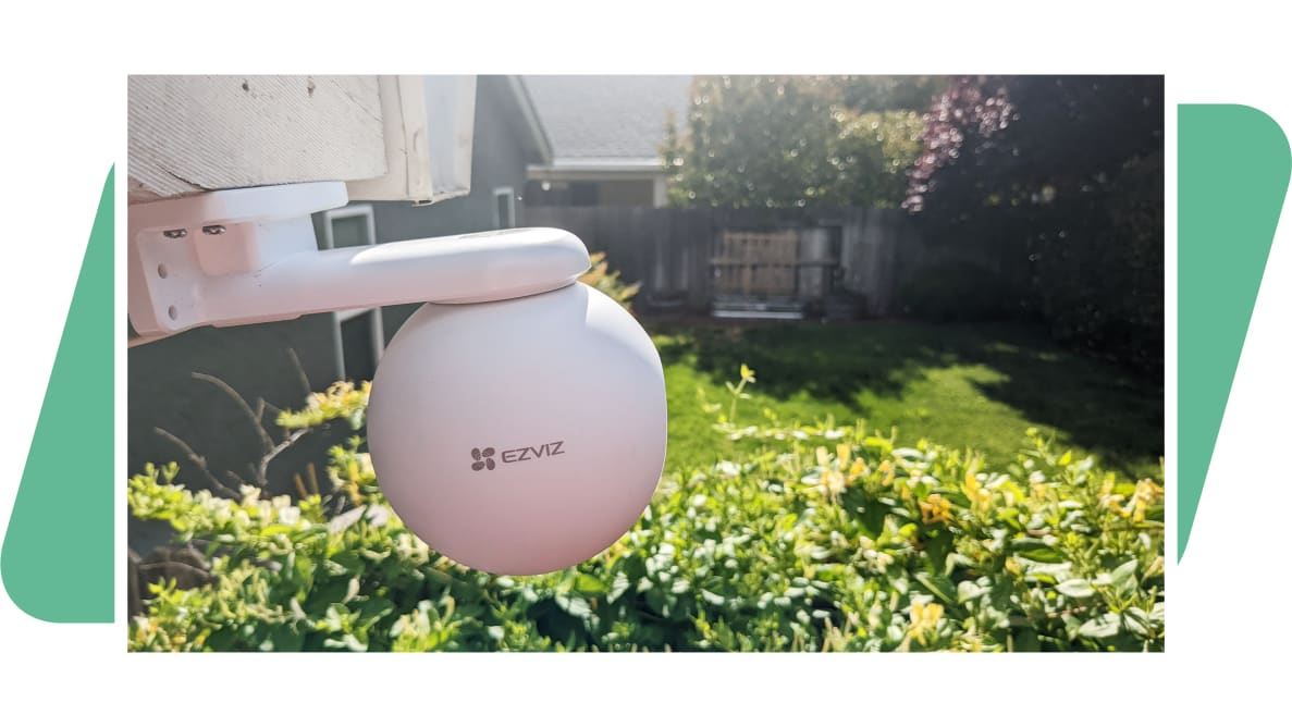 The EzViz H8 Pro 3K outdoor camera, facing a backyard on a green background.