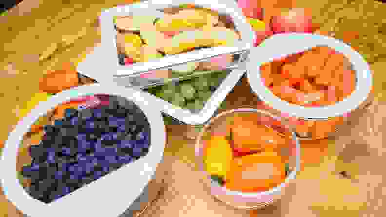 A variety of Pyrex Ultimate storage containers filled with produce sit on a wood counter.