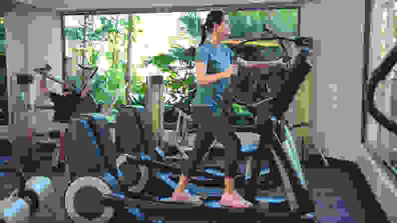 A woman using an elliptical machine at the gym.