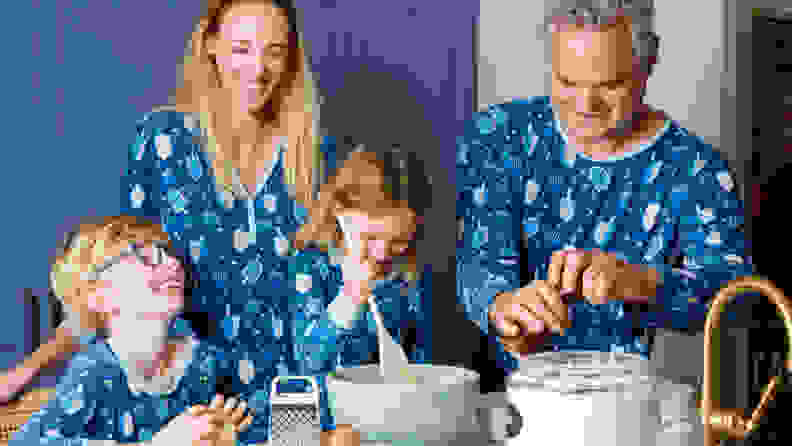 A family wearing matching Hanukkah pajamas making potato pancakes in a kitchen
