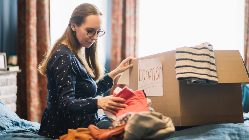 A person sorts through old clothes to donate.