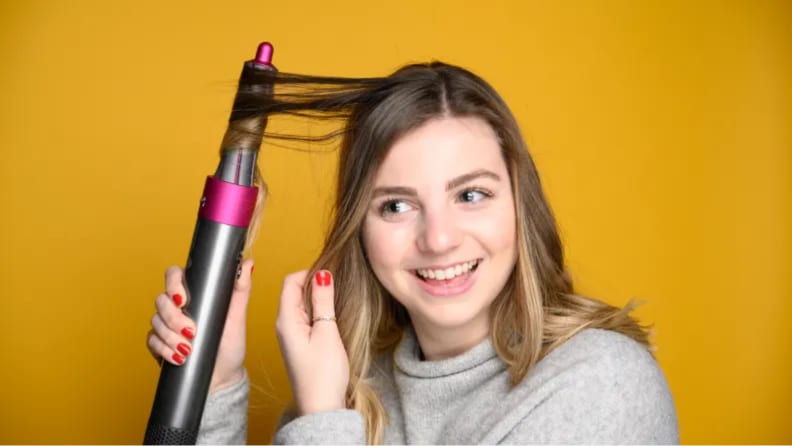 An image of a woman curling her hair around the Dyson Air Wrap.