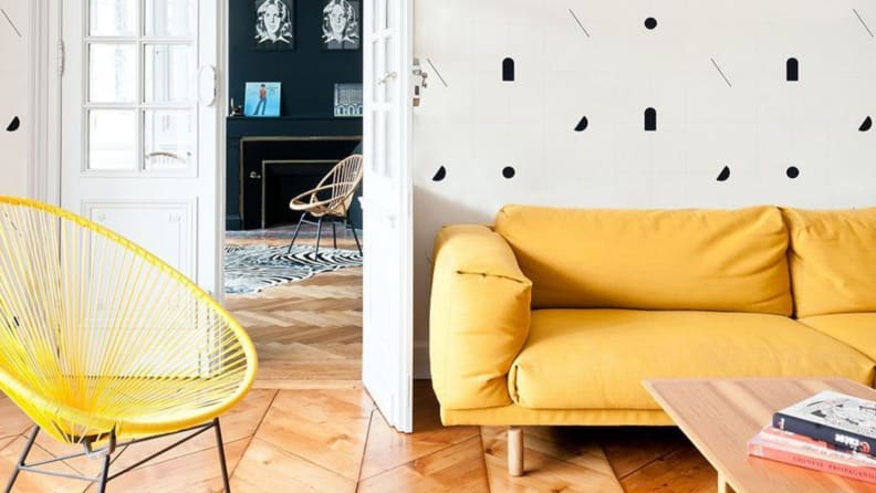 Living room with yellow couch and yellow chair with a white and navy wallpaper