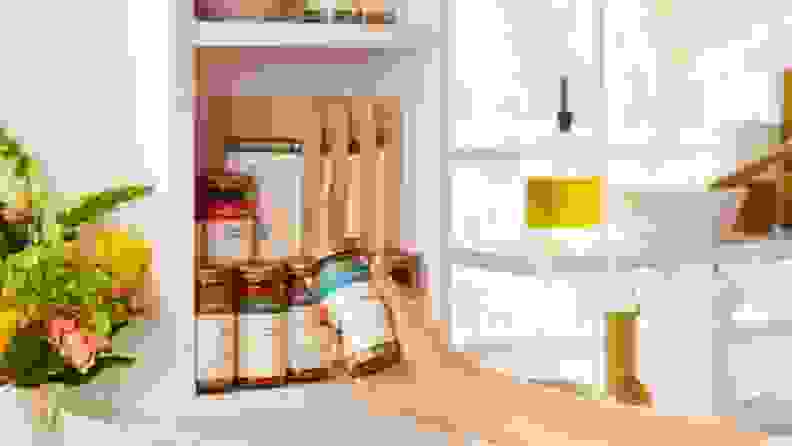A hand pulling a Spice House jar out of a cabinet filled with similar products.