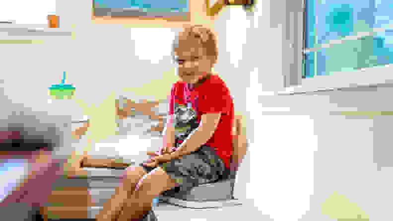 A boy sitting on a booster seat on a dining banquet.