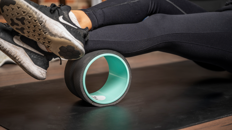 A woman using a Chirp yoga wheel on her legs.