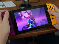 Person holds a Nintendo Switch while playing Fortnite