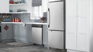 A silver refrigerator is in a kitchen next to a tall white pantry cabinet