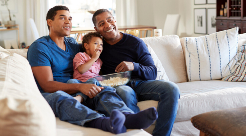 A family sits on the couch and watches TV