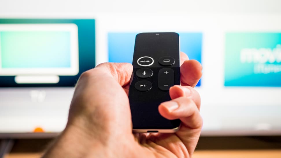 A person points an Apple TV remote to a smart TV.