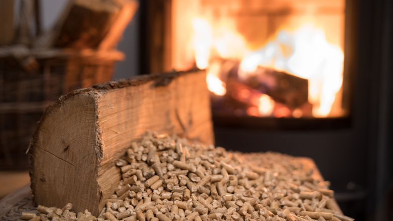 Wood logs and fuel pellets next to burning fire.
