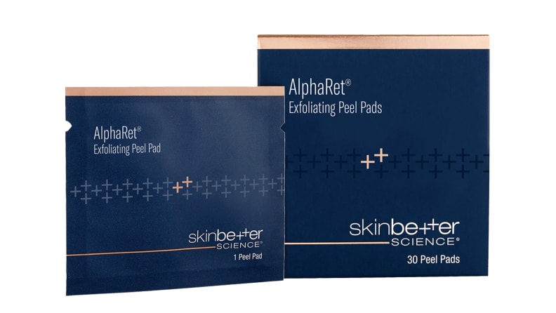 A navy blue box and a packet of exfoliating pads side by side on a white background.
