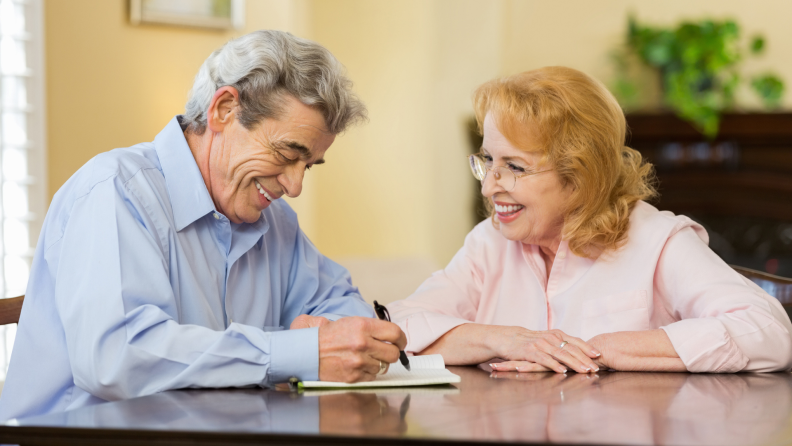 A senior couple finishing paperwork at home.