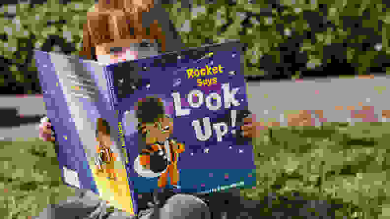 A child reads the book "Rocket Says Look Up!"