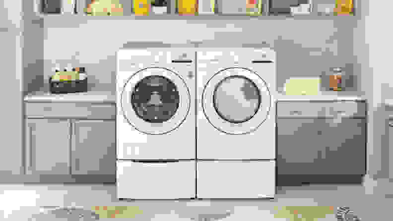 A white front-load washer and dryer pair in a laundry room setting surrounded by cabinets.