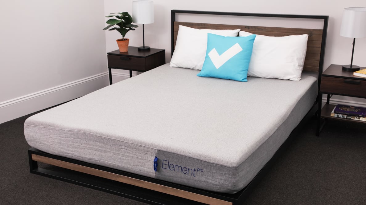The Casper Element Pro mattress set up in a bedroom set with the blue Reviewed checkmark pillow on it.