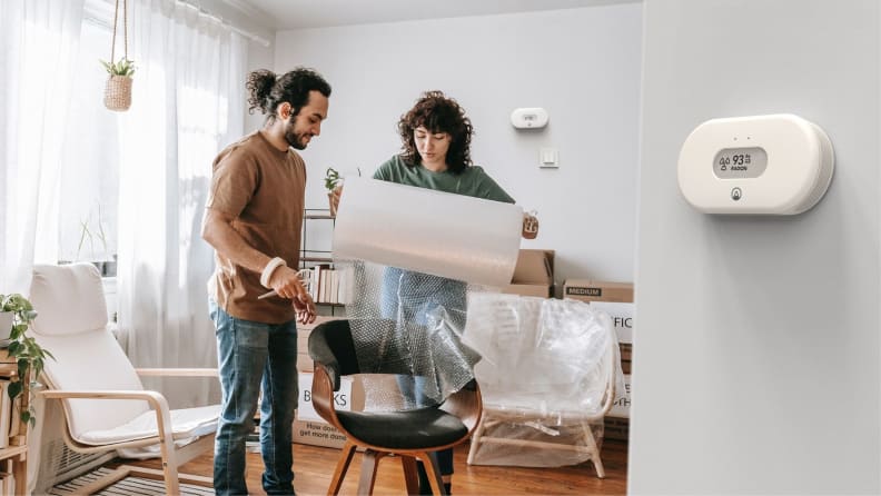 Couple unwrapping a new chair while Airthings View Radon monitors the air quality