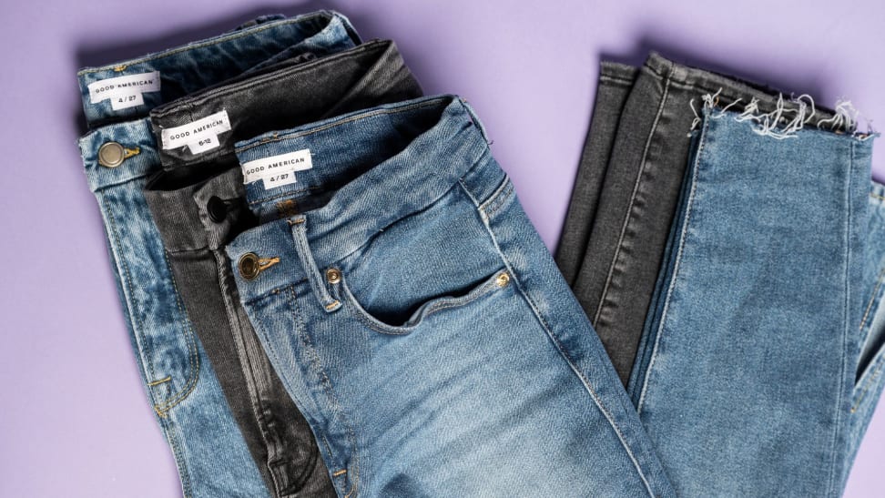 Three pairs of Good American jeans folded on a lavender background